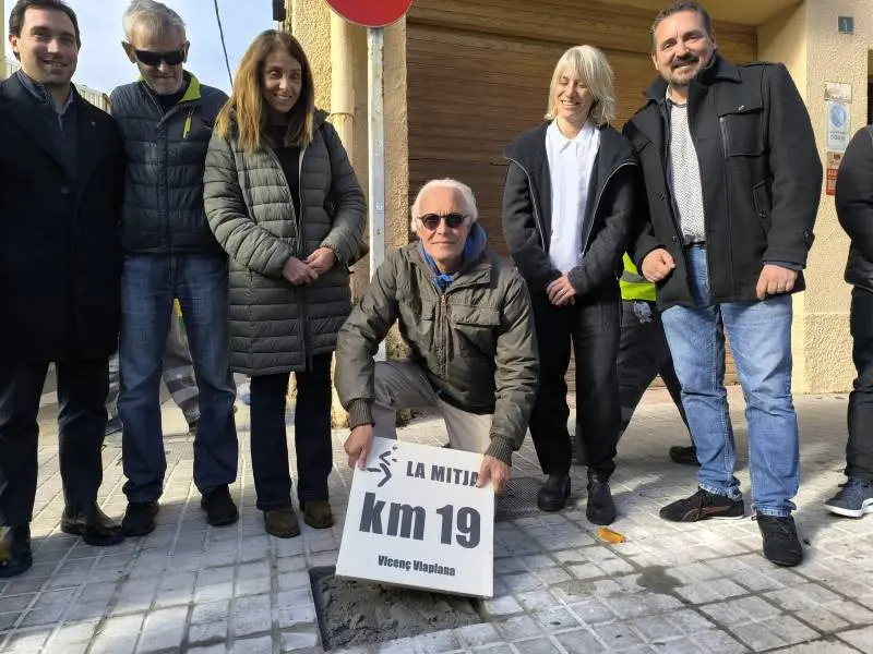 Vicen&ccedil; Viaplana col.locant la seva placa al km 19 de la Mitja