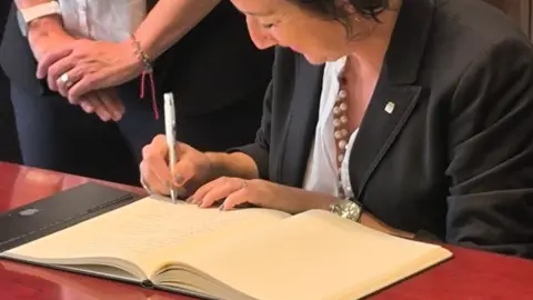 La consellera signant el llibre d'honor de lña ciutat