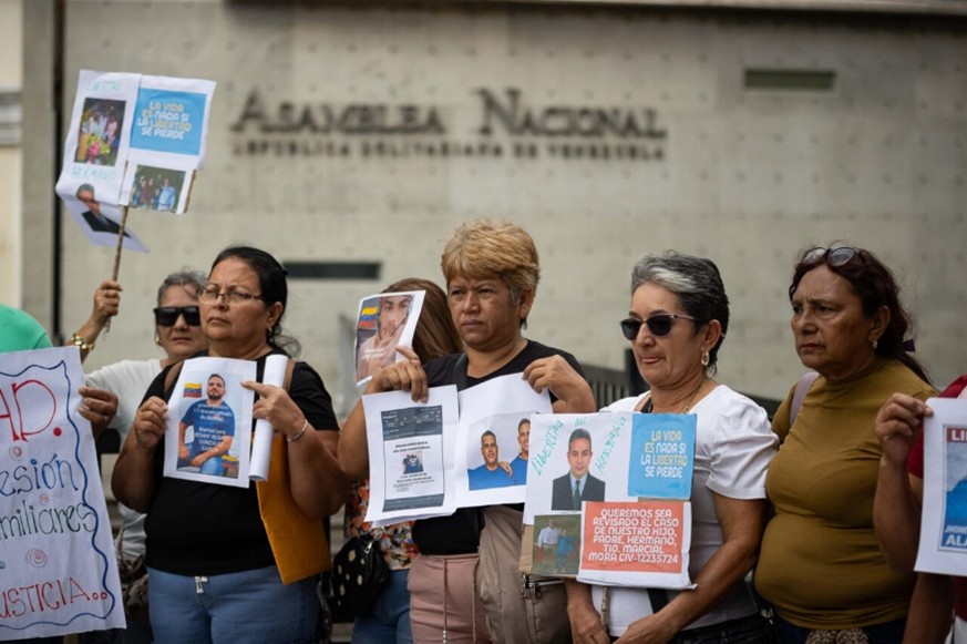 Personas sostienen carteles durante una manifestación este jueves , frente a la Asamblea Nacional en Caracas (Venezuela)